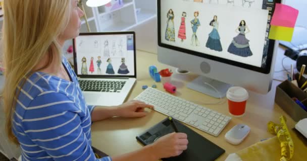 白种女性时装设计师在办公室办公桌前使用图形平板电脑的侧视图 她正在看电脑4K — 图库视频影像