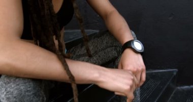 Şehirde merdivenlerde dinlenen genç Afro-Amerikan kadının yan görünümü. O yorgun ve yorgun 4k