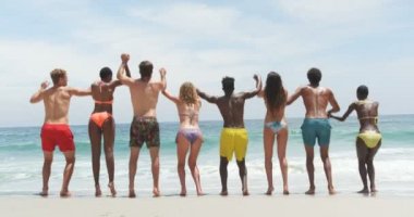 Front view of mixed-race friends jumping together on the beach. They are having fun 4k