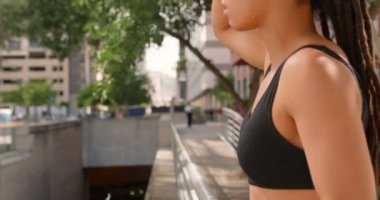 Şehirde bir köprü üzerinde duran genç Afro-Amerikan kadının yan görünümü. O terleme ve uzak 4k bakıyor