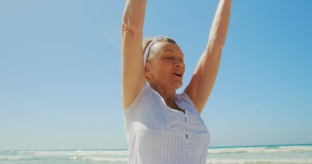 活跃高级白种妇女在海滩上做瑜伽的前视图 她闭着眼睛沉思 — 图库视频影像