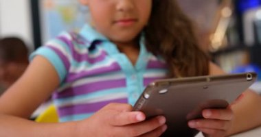 Sınıfta dijital tablet üzerinde okuyan Asyalı kız öğrencinin ön görünümü. 4k