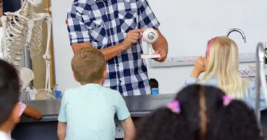 Sınıfta model açıklayan Kafkas erkek öğretmenin ön görünümü, Okul çocukları erkek öğretmeni dinliyor 