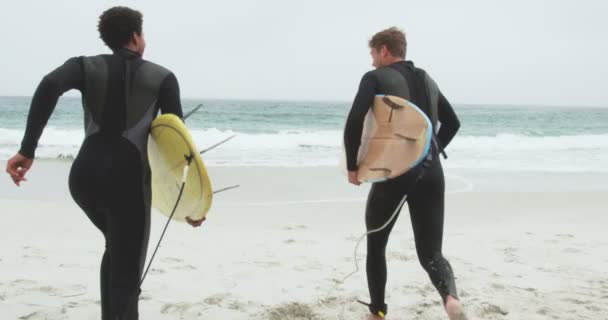 两个男冲浪者和冲浪板一起在海滩上奔跑的后视镜 他们在互相交流4K — 图库视频影像