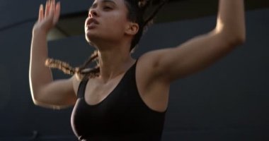 Şehirde saçlarını kaldıran genç Afro-Amerikan kadının ön görünümü. O bir köprü 4k yanında duruyor