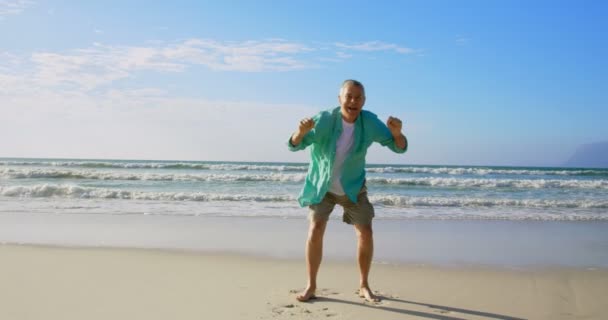 活跃高级白种人男子在海滩上跳跃的前视图 他很兴奋 — 图库视频影像