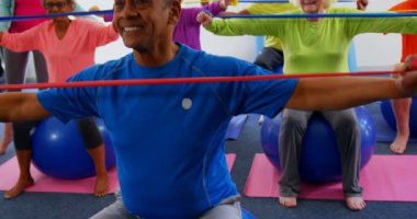 Fitness stüdyosunda egzersiz üst düzey insanlar kafkas kadın eğitmen eğitim Ön görünümü. Direnç bandı ile egzersiz yapıyorlar. 