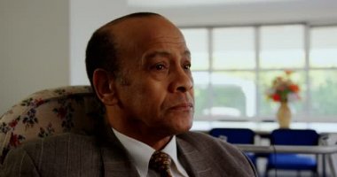 Huzurevinde dinlenen Asyalı yaşlı adamın ön görünümü. Kameraya bakıyor. 