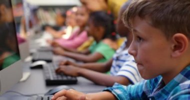 Sınıfta bilgisayarda okuyan karma ırklı okul çocuklarının yan görünümü. Kadın öğretmen öğretim okul çocukları 