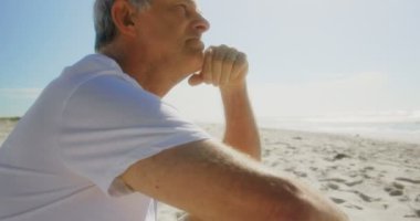 Sahilde dinlenen aktif kıdemli Kafkas adamın yan görünümü. O düşünceli bir ruh hali 4k olduğunu