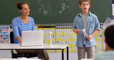 Sınıfta yel değirmeni modeli hakkında açıklayan Kafkas öğrenci nin ön görünümü. Sınıfta oturan öğrenciler 