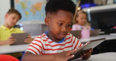 Sınıfta dijital tablet kullanarak Afrikalı Amerikalı öğrencinin ön görünümü. Sınıfta oturan öğrenciler 