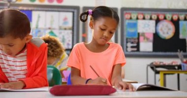 Sınıfta not defterine çizim karışık ırk okul çocukları ön görünümü. Sınıfta oturuyorlar. 