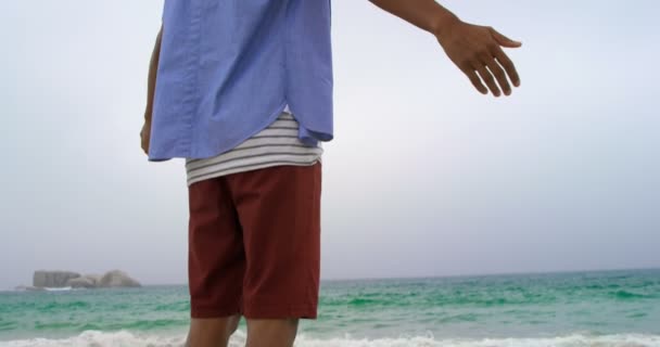 低角度的非洲裔美国人站在手臂上伸出在沙滩上 他正在看海4K — 图库视频影像