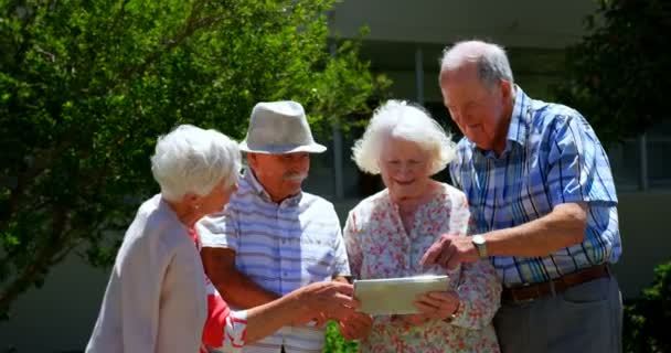 Ομάδα Καυκάσιων Ηλικιωμένων Που Συζητούν Για Ψηφιακό Δισκίο Στον Κήπο — Αρχείο Βίντεο