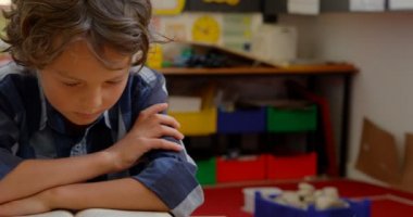 Okulda sınıfta masa başında okuyan Kafkas öğrencinin ön görünümü. O bir kitap 4k okuyor