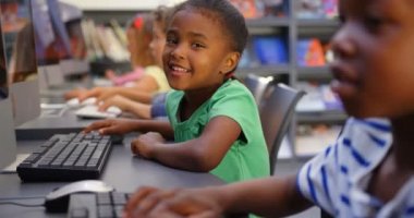 Sınıfta bilgisayarda okuyan karma ırklı okul çocuklarının yan görünümü. Sınıfta oturuyorlar. 