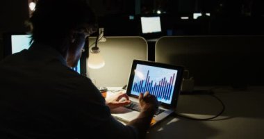 Modern bir ofiste masa başında dizüstü bilgisayar üzerinde çalışan genç Kafkas erkek yöneticinin arka görünümü. Kahve içiyor 4k.