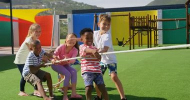 Okul bahçesinde römorkör oynayan melez okul çocuklarının ön görünümü. Birlikte eğleniyorlar. 