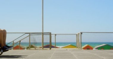 Aktif kıdemli Beyaz kadın sahilde tekerlekli sandalyede kıdemli adam iterek yan görünümü. Birbirleriyle etkileşime giriyorlar 4k