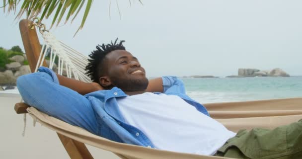 Vista Frontal Del Hombre Afroamericano Relajándose Una Hamaca Playa Sonríe — Vídeo de stock