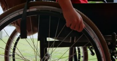 Okul koridorunda tekerlekli sandalyesini hareket ettiren engelli Afro-Amerikan öğrencinin yan görünümü. Tekerlekli sandalye 4k tekerleğiitiyor