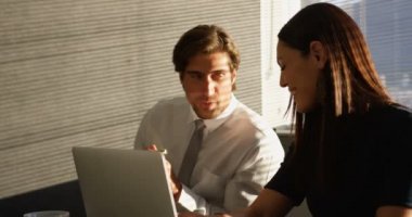 Modern bir ofiste masa başında çalışan genç Kafkas ofis yöneticilerinin ön görünümü. Konuşuyorlar ve gülümsüyorlar. 