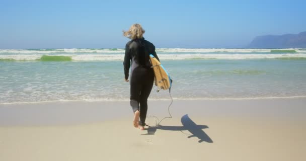 Visão Traseira Surfista Feminino Caucasiano Sênior Ativo Que Corre Mar — Vídeo de Stock