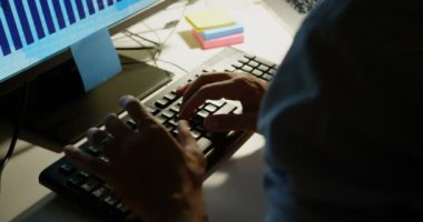 Modern ofiste masa başında bilgisayar üzerinde çalışan genç Kafkas erkek yöneticiyan görünümü. Bilgisayar ekranında iş grafiği 4k