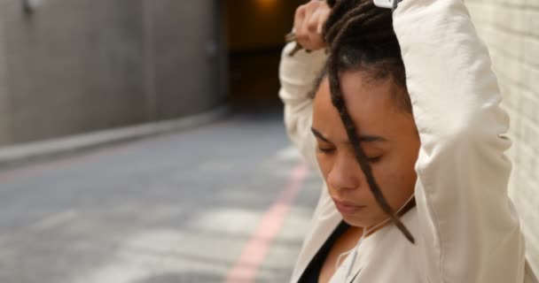 年轻的非洲裔美国妇女在城市中绑着她的上一面 她正在听音乐4K — 图库视频影像