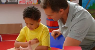 Sınıfta Afro-Amerikan öğrenci öğretim genç Kafkas erkek öğretmen ön görünümü. Masada oturuyorlar. 