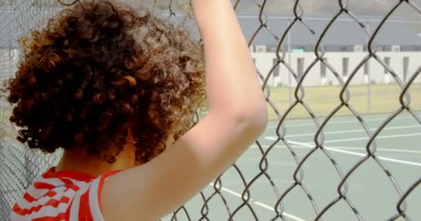 Achteraanzicht Van Een Gemengde Schooljongen Bij Een Hek Met Gaas — Stockvideo