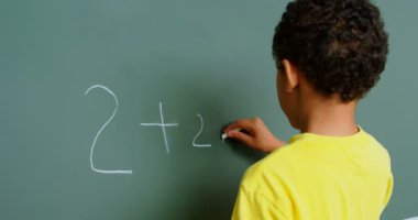 Afrika kökenli Amerikalı bir öğrencinin okuldaki karatahtayla matematik problemini çözmesi. Ek iş olarak 4K yapıyor.