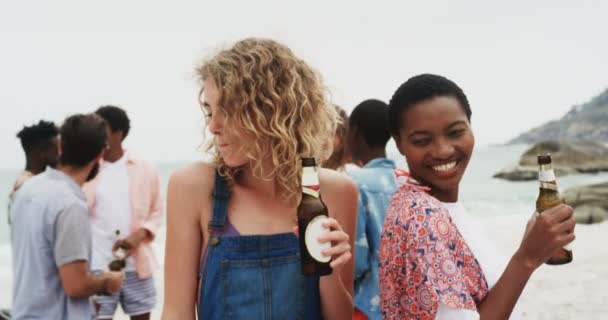 ビーチで一緒に踊る混合レースの女性の友人のフロントビュー ビールを飲んでる4K — ストック動画