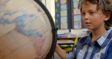 Okulda sınıfta masa başında dünya okuyan Kafkas öğrencinin ön görünümü. O bakıyor ve dünya 4k iplik