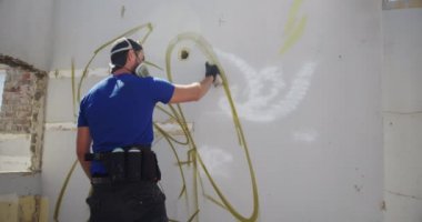 Duvarda aerosol sprey ile kafkas grafiti sanatçısı boyama arka görünümü. O koruyucu maske 4k giyiyor