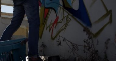 Beyaz grafiti sanatçısının gün ışığında duvara bakan düşük açılı görünümü. O aerosol can 4k tutuyor