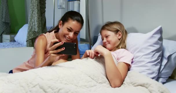 病院病棟の携帯電話でビデオ通話をする白人の母親と娘の正面図 彼らは4K笑っている — ストック動画
