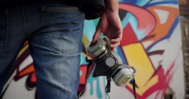 Koruyucu maske tutan Kafkas grafiti sanatçısının orta bölümü. O grafiti duvar 4k önünde duruyor