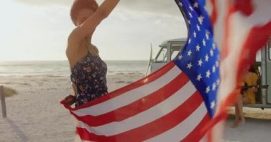 Plajda kamp minibüsü yakınında gitar çalan ve şarkı söyleyen çok ırklı arkadaşlardan oluşan bir grup. Amerikan bayrağı 4k ile dans kadın