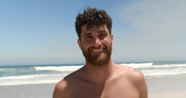 Vooraanzicht Van Jonge Kaukasische Man Staande Het Strand Terwijl Glimlachend — Stockvideo