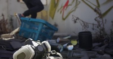Duvarda aerosol sprey ile kafkas grafiti sanatçısı boyama yan görünümü. Zeminde koruyucu maske 4k