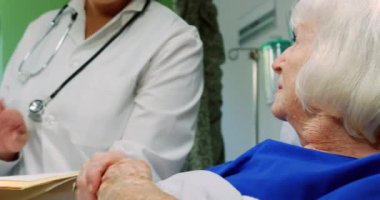 Kafkas kadın doktorunun orta bölümü hastanedeki koğuşta aktif kıdemli hastayla etkileşime geçiyor. 4K raporunu tutuyor.