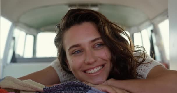 4Kを見つめながらビーチでキャンピングカーでくつろぐ美しい若い白人女性の正面図 — ストック動画