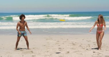 Güneşli 4k plajda uçan disk ile oynarken gülümseyen ve eğlenen genç çok etnik arkadaşlar Ön görünümü