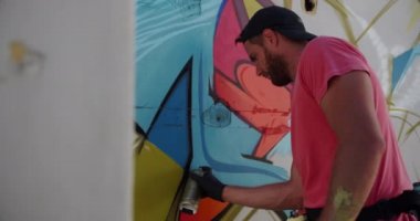 Duvarda aerosol sprey ile kafkas grafiti sanatçısı boyama yan görünümü. O yaratıcı 4k
