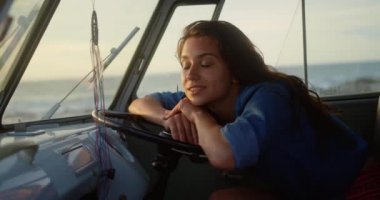 Sahilde karavanda dinlenen Kafkas kadının yan görünümü. O gülümsüyor ve uzağa 4k bakıyor