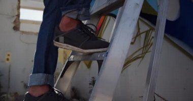 Duvarda aerosol sprey ile kafkas grafiti sanatçısı boyama düşük açı görünümü. Merdiven 4k kullanıyor.
