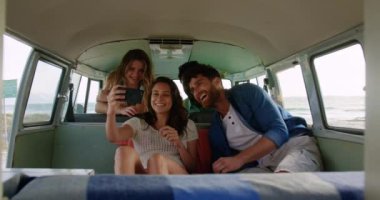 Sahilde karavanda selfie çeken çok ırklı genç bir grup genç arkadaş ön görünüm. Onlar gülümsüyor ve eğleniyor4k