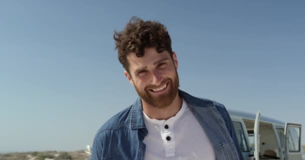 年轻的白种人男子站在沙滩上 面带微笑 看着相机在阳光下4K前视图 — 图库视频影像